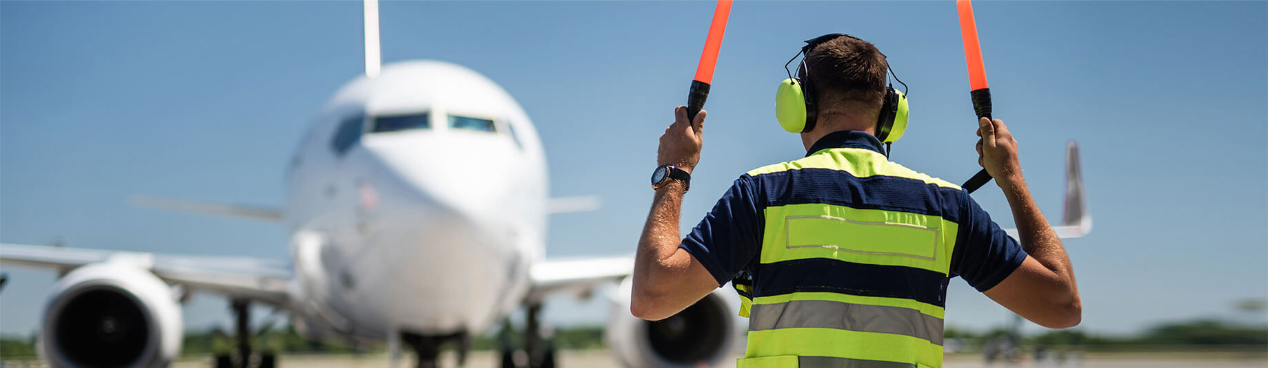 Image of airport ground crew member directing plane 