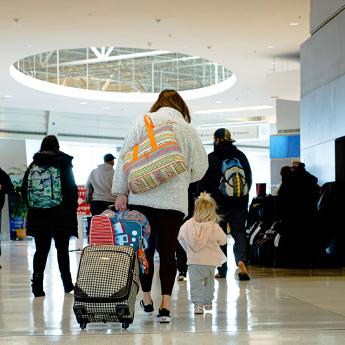 Woman and child walking through airport pulling luggage