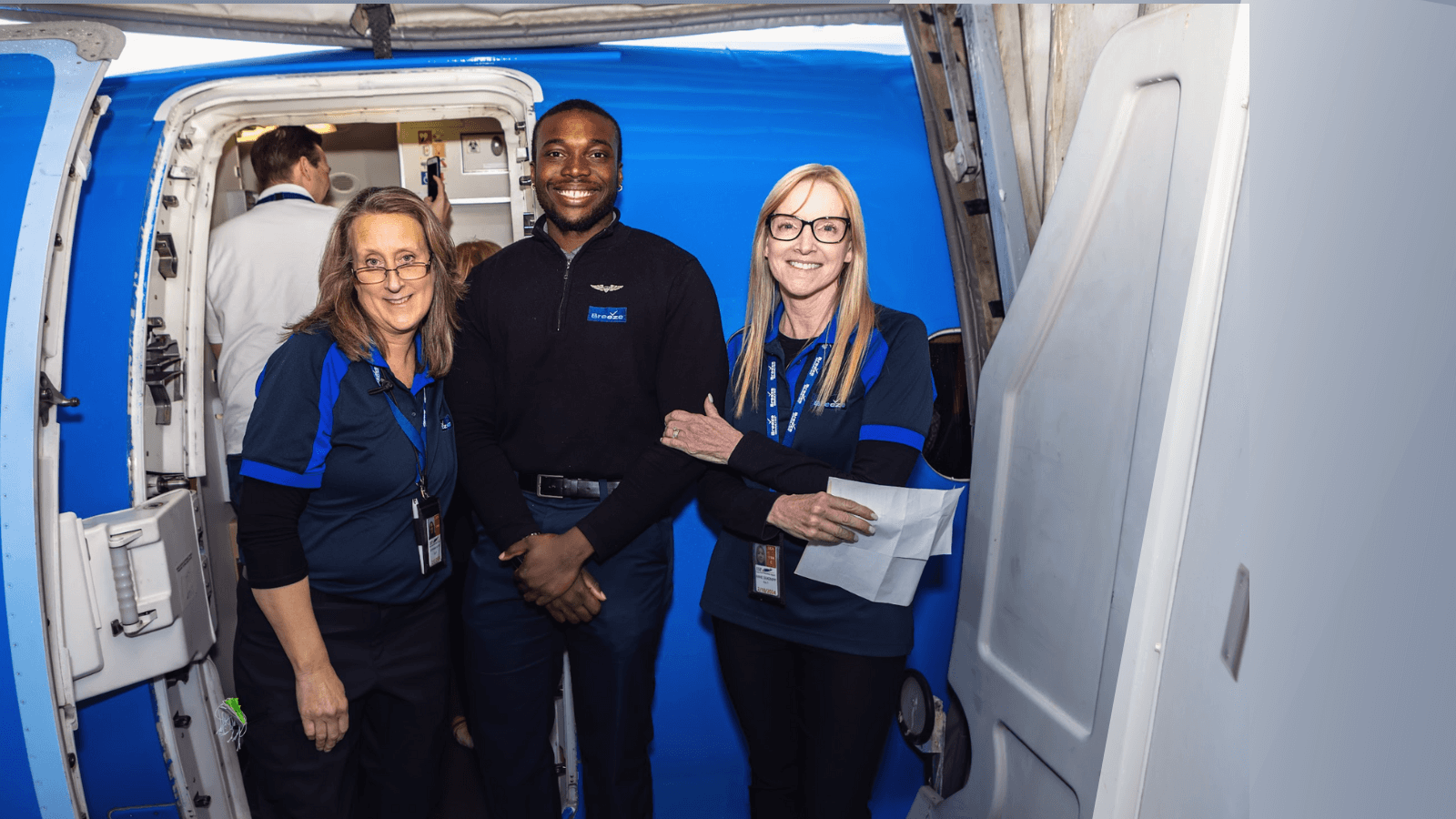 Breeze Airline employees pose for picture outside airplane