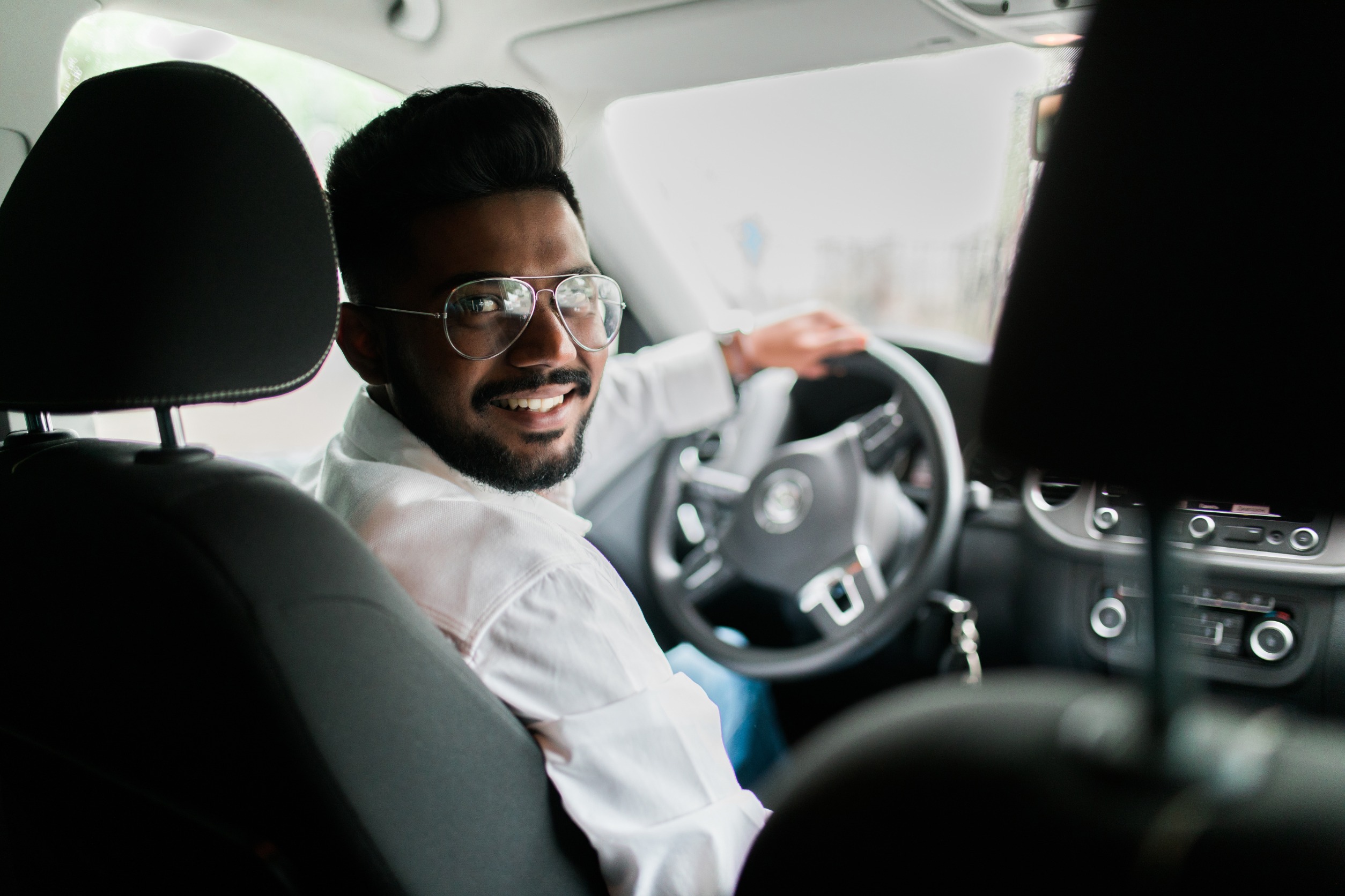 Man behind wheel of vehicle smiling at camera 