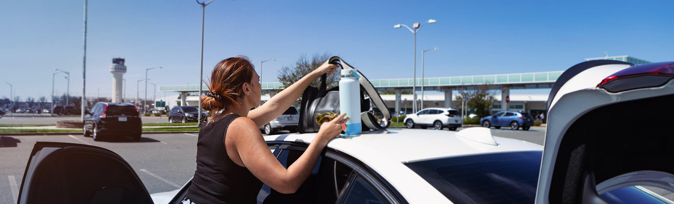Woman placing water bottle on top of vehicle at the MacArthur Airport
