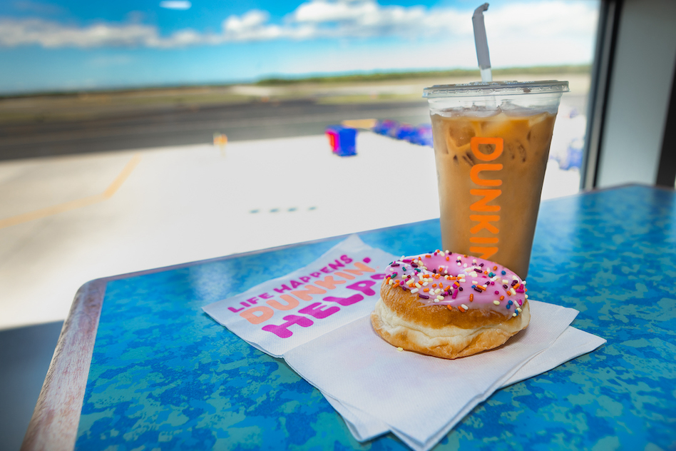 A Dunkin coffee cup and donut sitting at a window at ISP airport